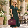 Woman in a green dress holding a bordeaux Womens Leather Shopper Bag, showcasing elegance and style in an outdoor setting.