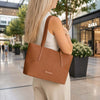 Woman carrying a Woven Leather Shopping Bag in an outdoor shopping area.