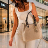 Woman holding Woven Leather Bag in shopping mall, showcasing its stylish design and golden hardware.